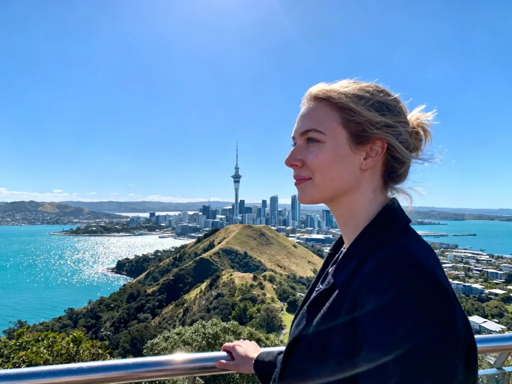 Turystka podziwiająca panoramę Auckland ze Sky Tower oraz malowniczą zatokę Waitematā w słoneczny dzień.